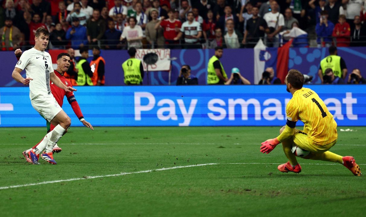 El portero esloveno Jan Oblak (d) evita el gol de Cristiano Ronaldo en los últimos minutos del partido de octavos de final entre Portugal y Eslovenia en Frákfort, Alemania.EFE/EPA/ANNA SZILAGYI